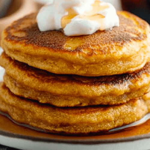 Stack of golden brown hoe cakes with butter and syrup on white plate